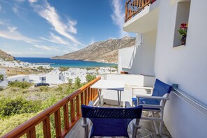A balcony with a view of the sea, white buildings, and a wooden railing. - Froudi (Sifnos)
