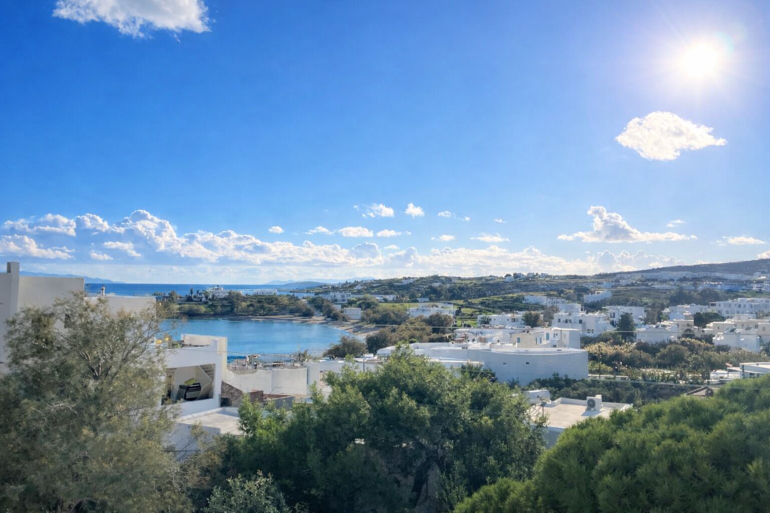 A coastal town with buildings, a body of water, and a clear sky.