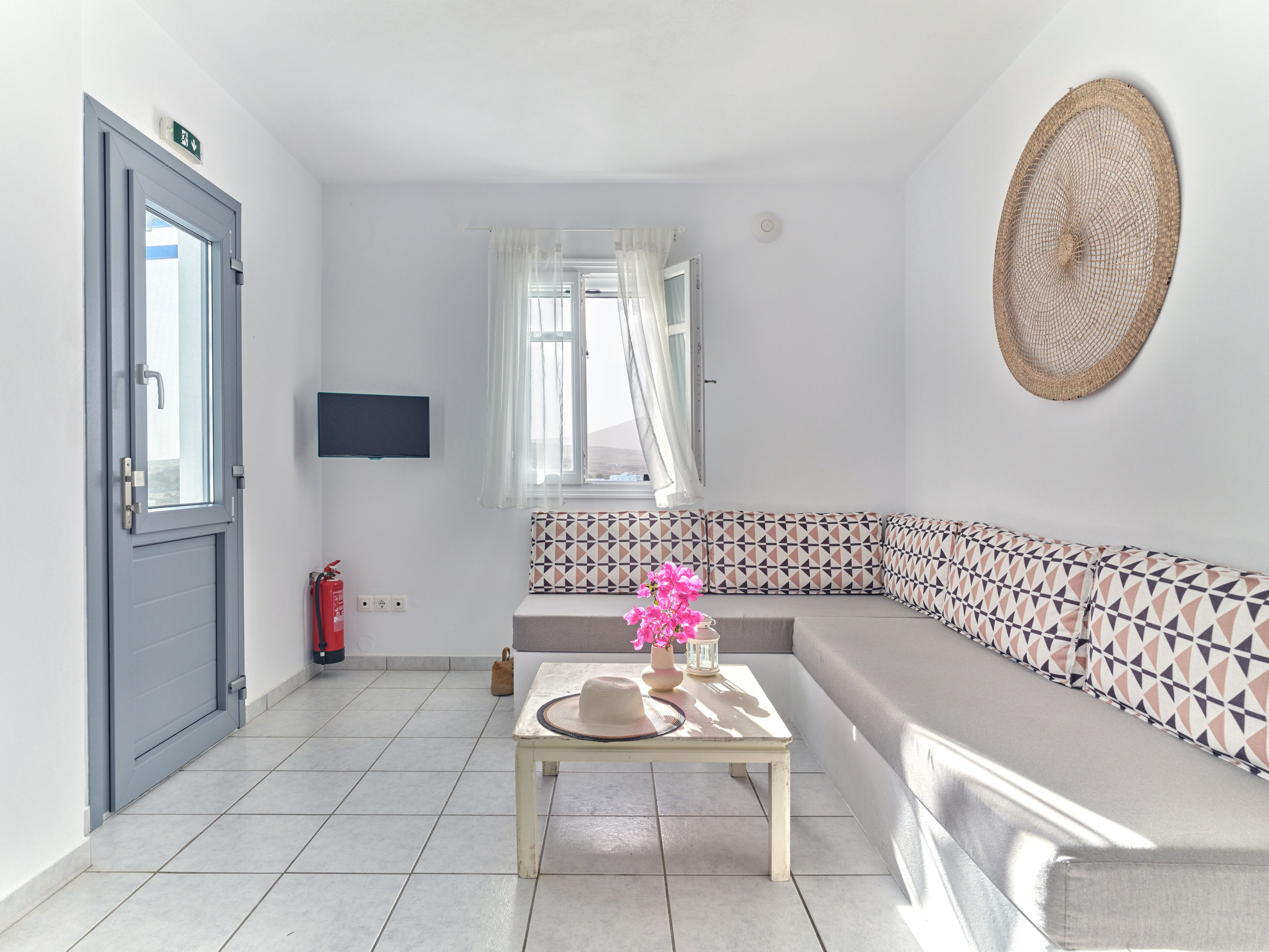 Ein modernes Wohnzimmer mit einem grauen Sofa, einem kleinen Tisch mit einem Hut und einem an der Wand montierten Fernseher.