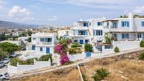 A coastal village with white buildings and blue shutters, a clear sky, and a distant view of the sea. - Cleopatra Seaside Homes Paros (Paros)