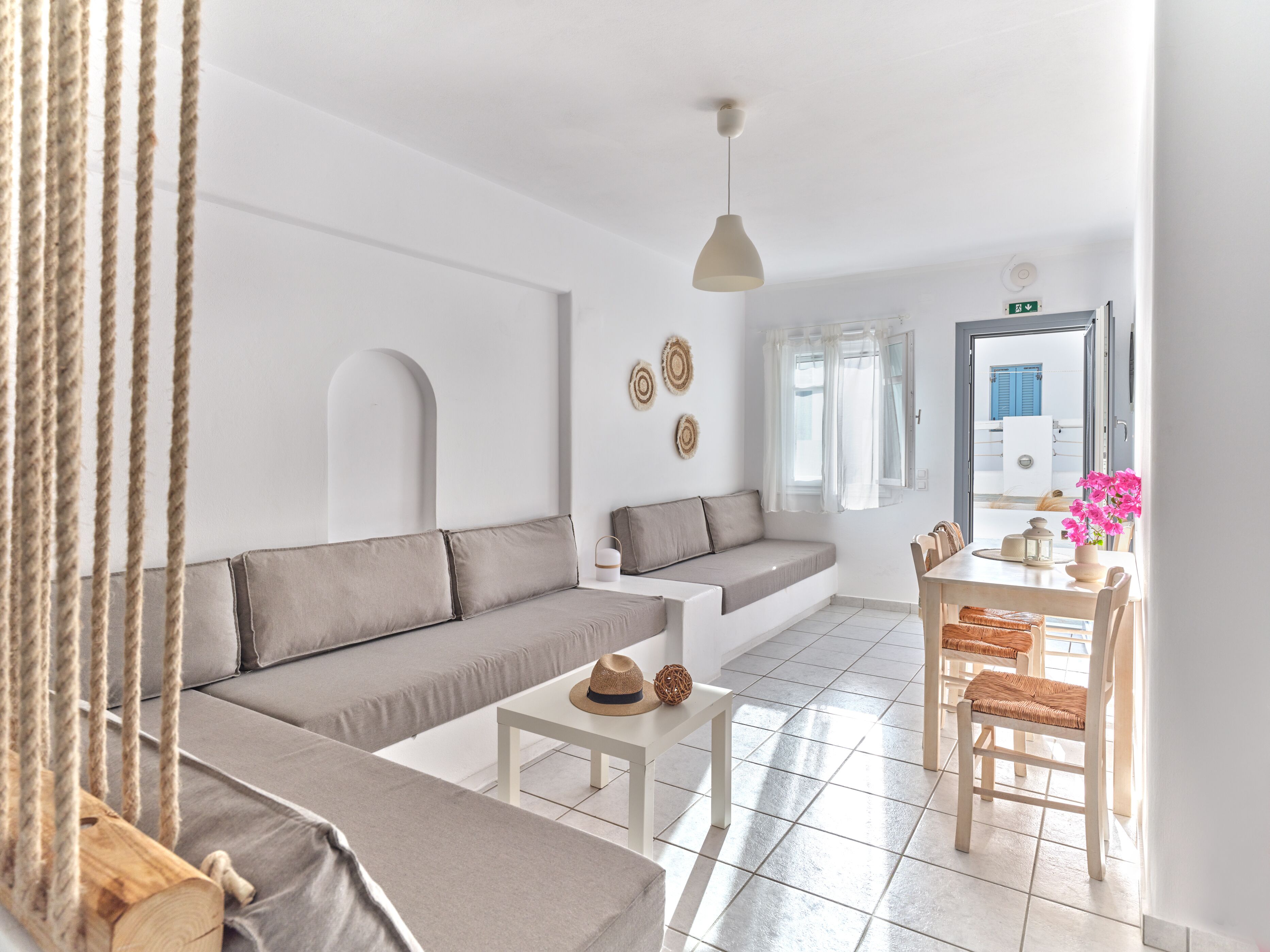 A modern living room with a sofa, a small table, and a dining area with chairs.