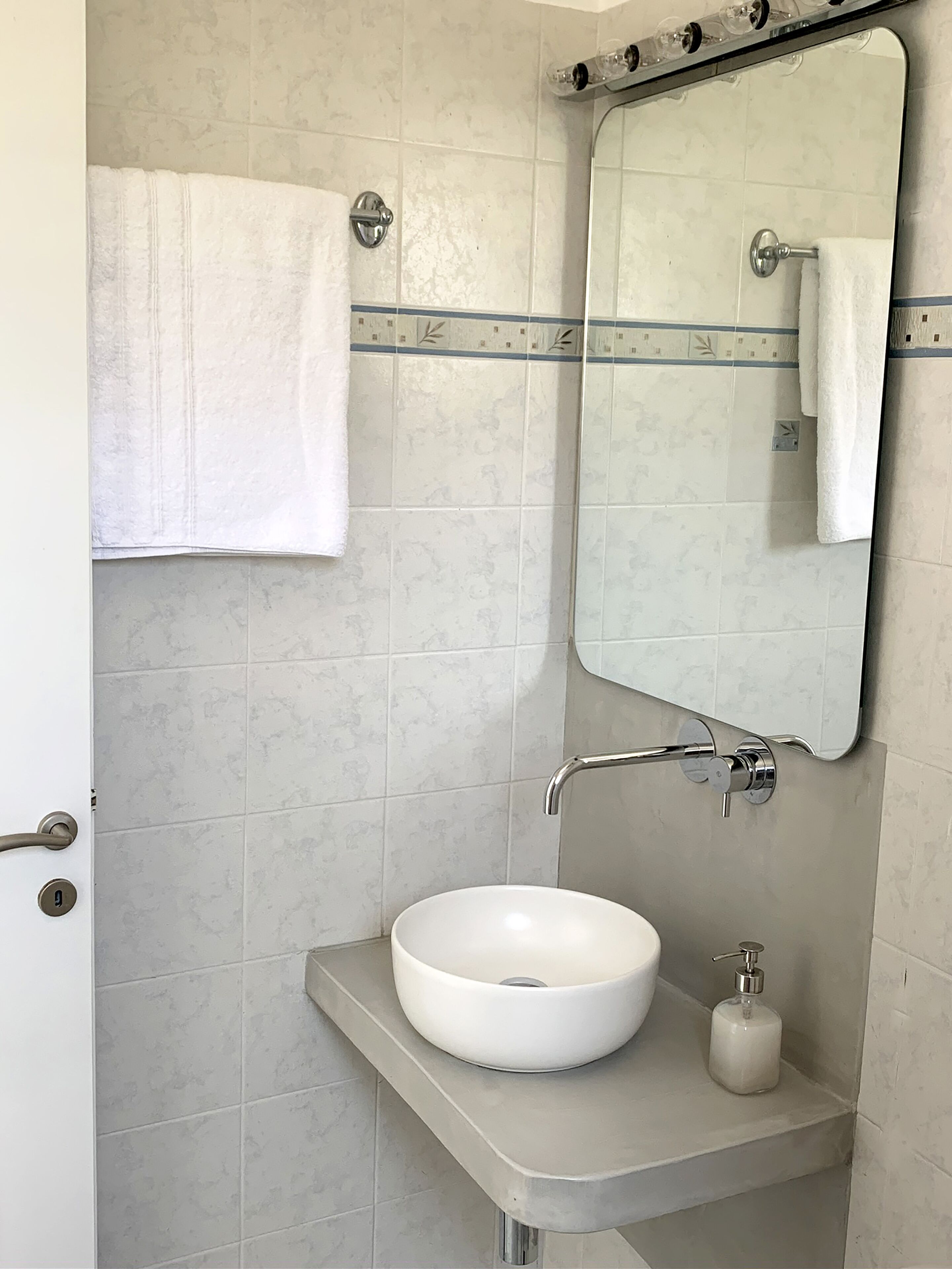 A bathroom with a white sink, a mirror, and a towel hanging on a rack.