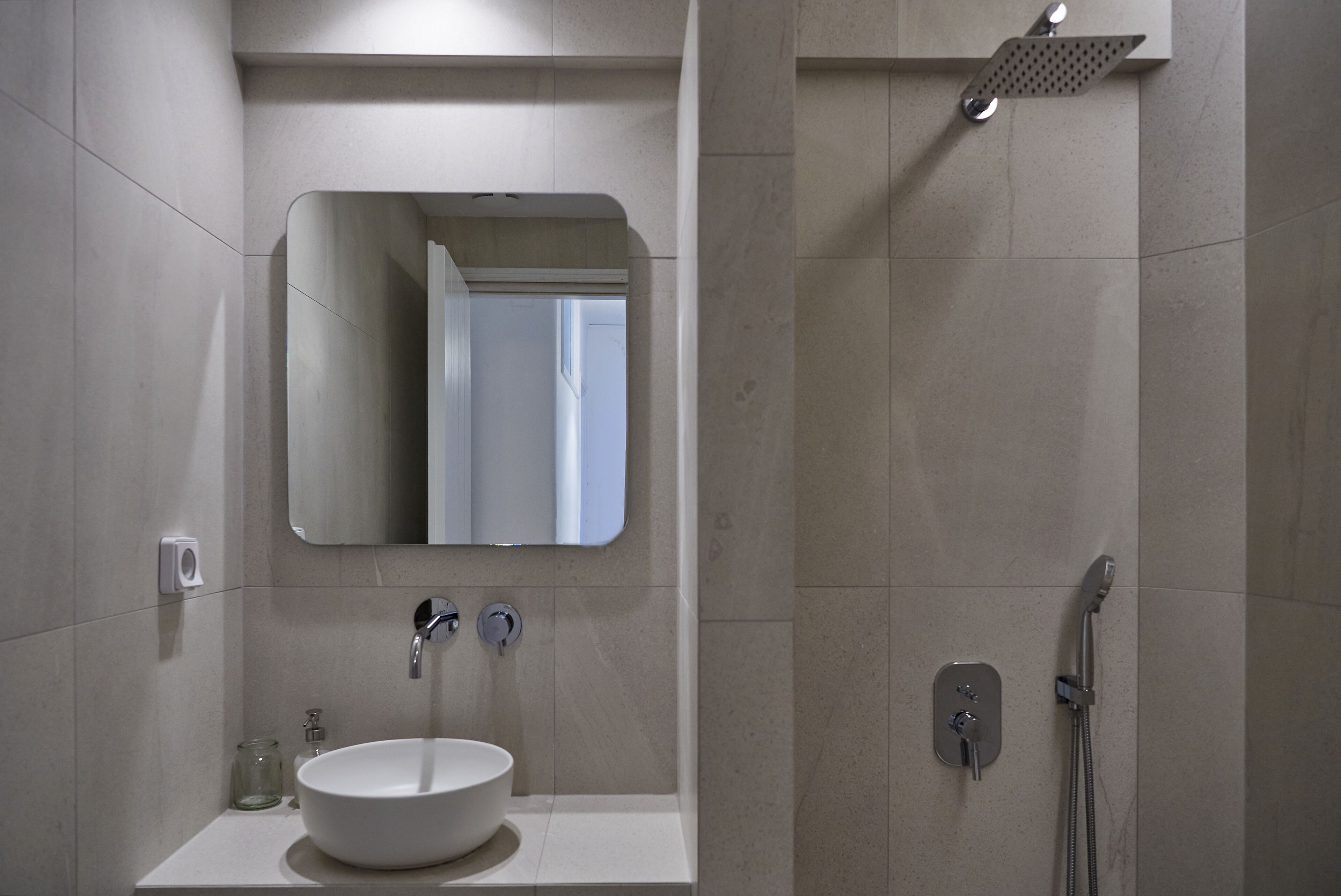 A modern bathroom with a white sink, mirror, and shower.