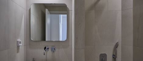 A modern bathroom with a white sink, mirror, and shower.