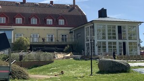 A two-story building with a red-tiled roof and a large windowed section. - Halltorps Gästgiveri (Borgholm)