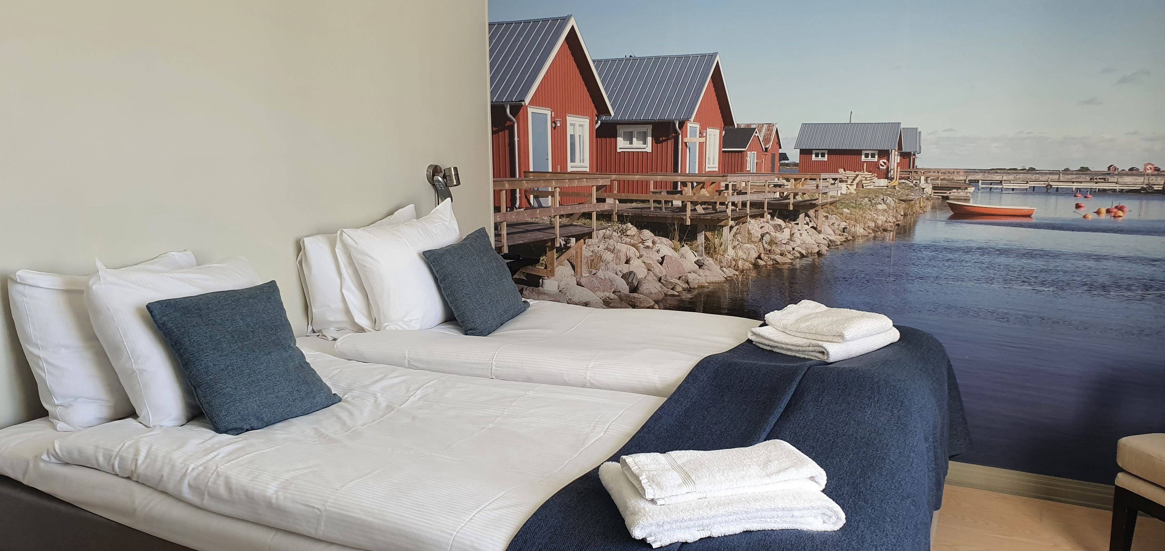 Une chambre d’hôtel avec un lit, des oreillers, une couverture et une vue sur le bord de l’eau, avec des maisons.