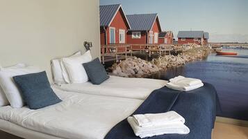Et hotelværelse med seng, puder, et tæppe og udsigt til en havnefront med huse.