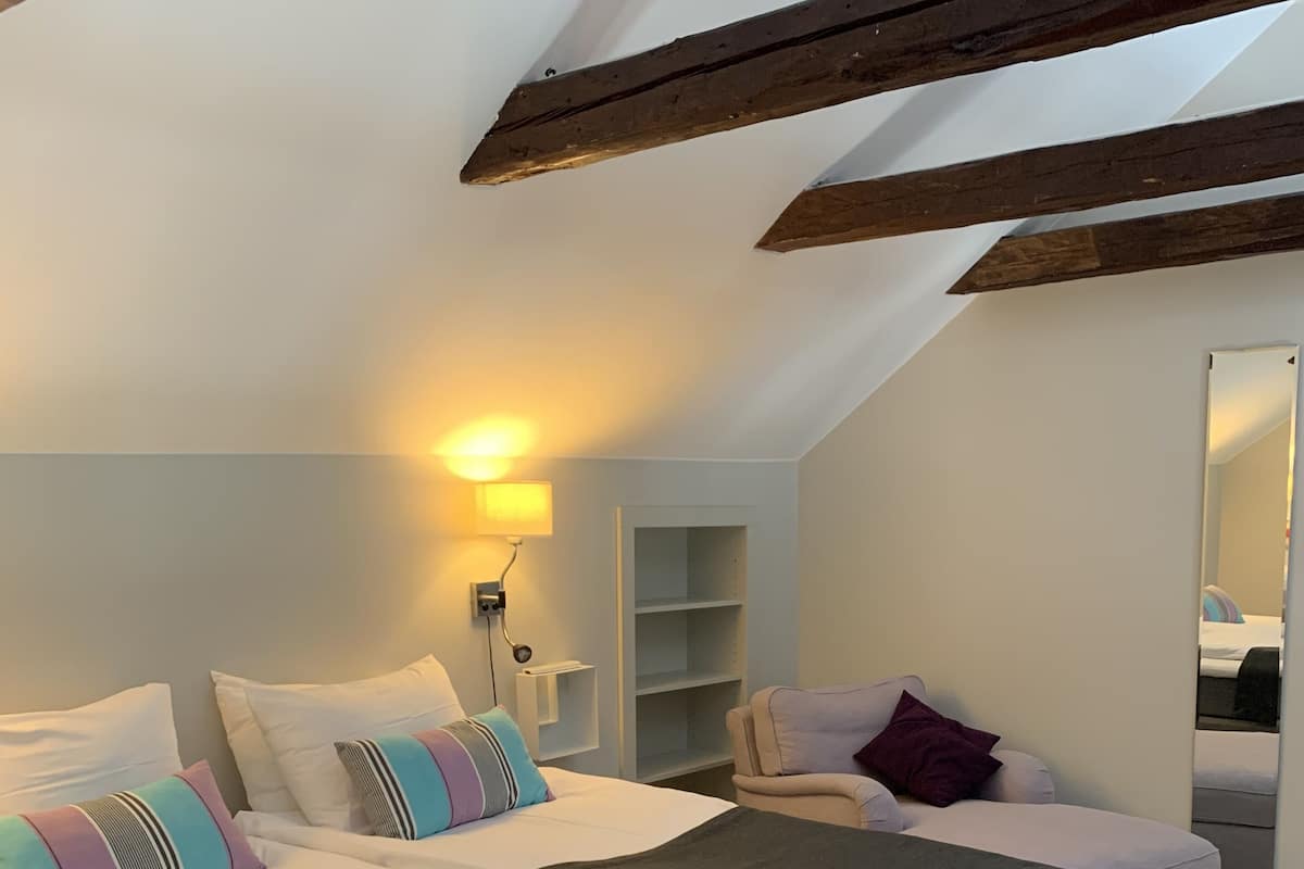 Ein Schlafzimmer mit einem großen Bett, einem Sessel, einem Nachttisch und einem Spiegel.