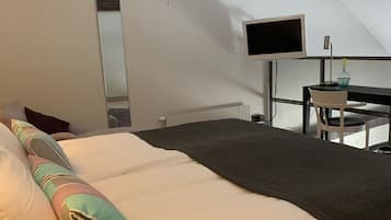 A bedroom with a bed, a desk, a chair, a TV, and a window.