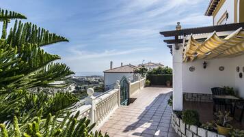 Una terraza con vistas al mar, una pérgola y una zona de comedor con mobiliario de exterior.