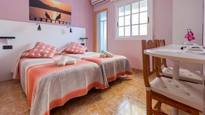 Een slaapkamer met twee bedden, een eettafel en een raam met uitzicht.