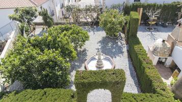 Un patio con una fuente central, rodeado de setos y árboles bien cuidados.