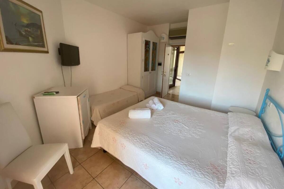 A hotel room with a bed, a desk, a chair, and a television.