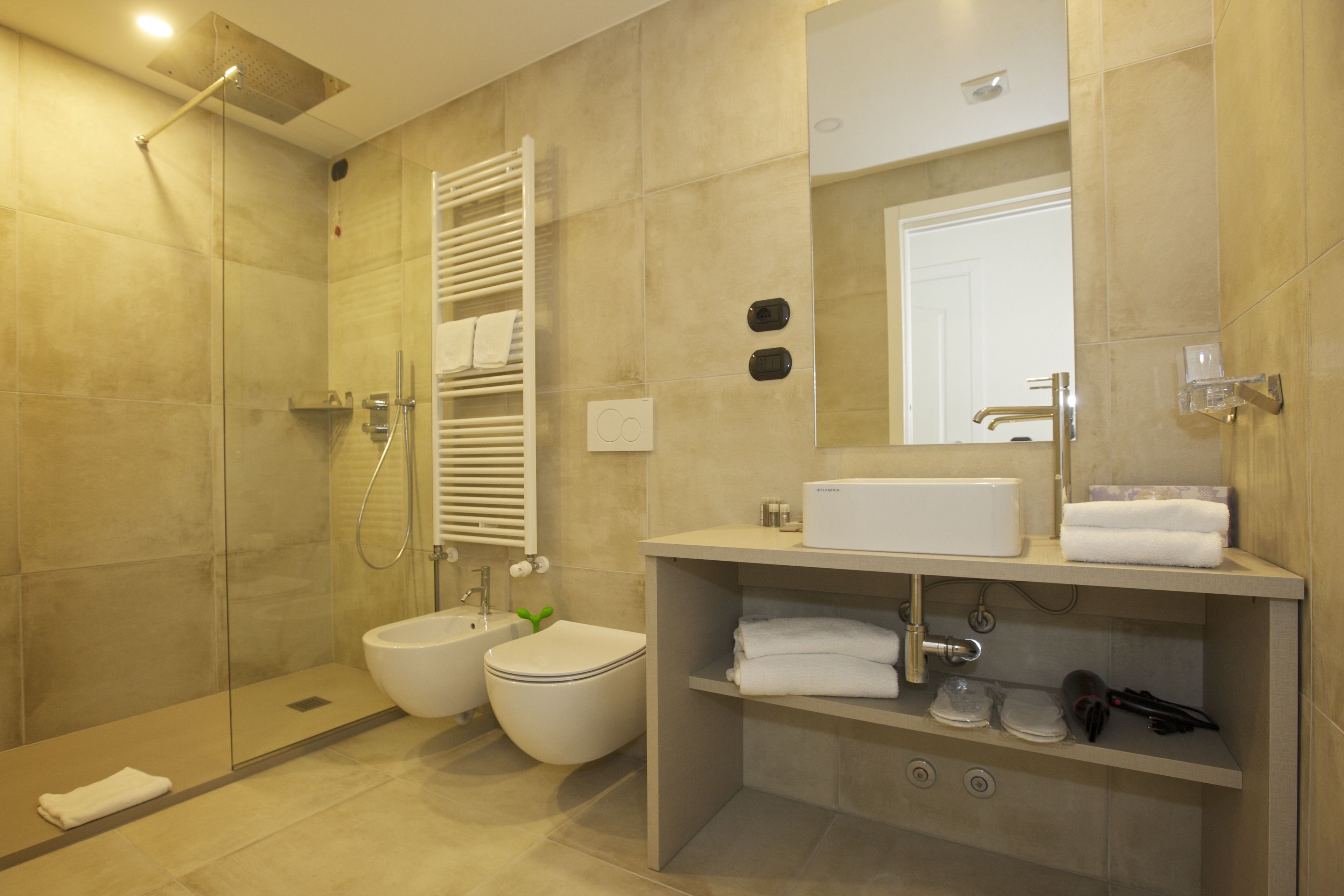 A modern bathroom with a glass-enclosed shower, a toilet, and a sink with a mirror above it.