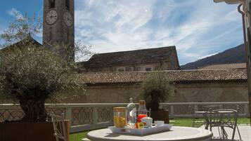 An outdoor patio with a round table and chairs, a clock tower in the background, and a clear sky.