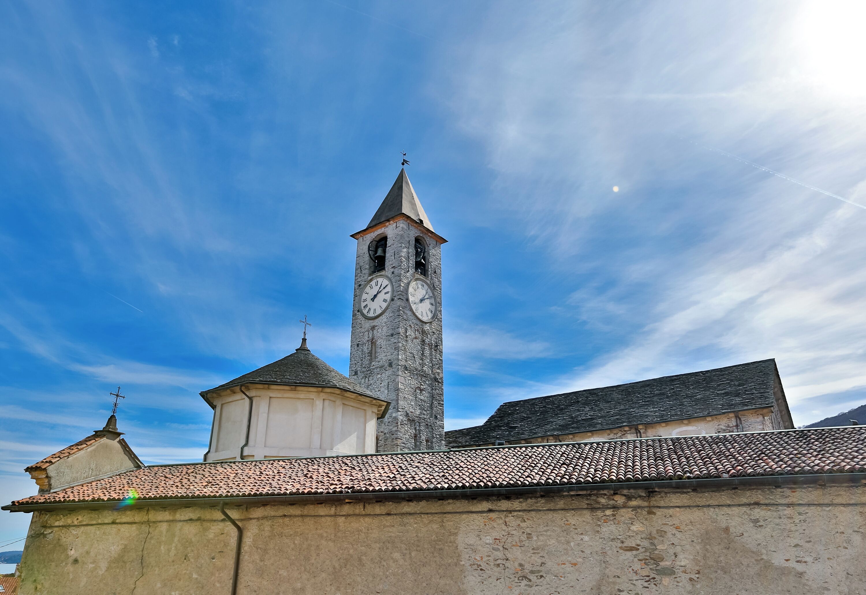 A historic building with a prominent clock tower, a smaller adjacent structure, and a tiled roof.