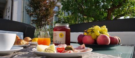 A breakfast table with croissants, fruit, and a bottle of jam.