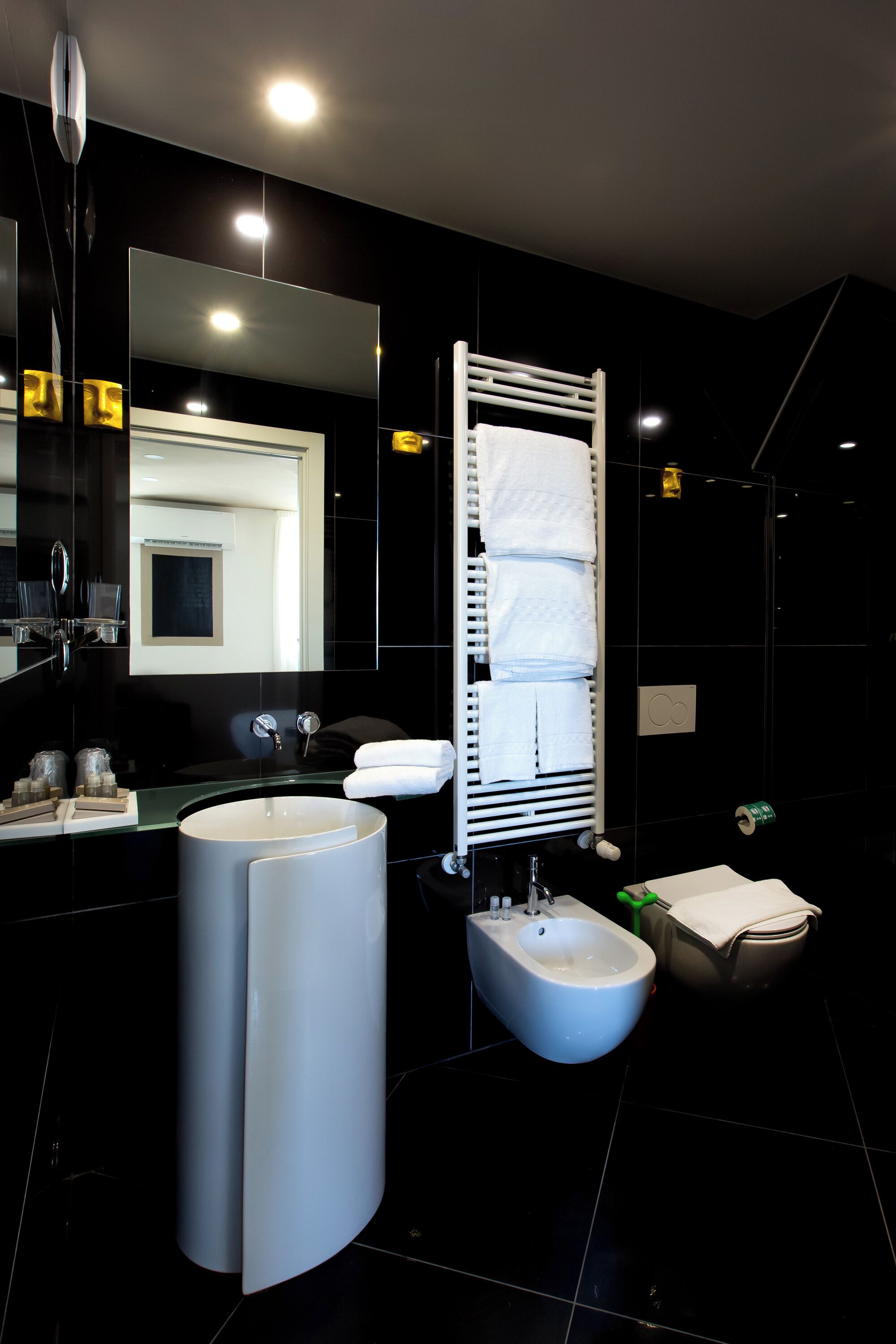 Un baño moderno con un bidé, un espejo grande y un perchero para toallas.