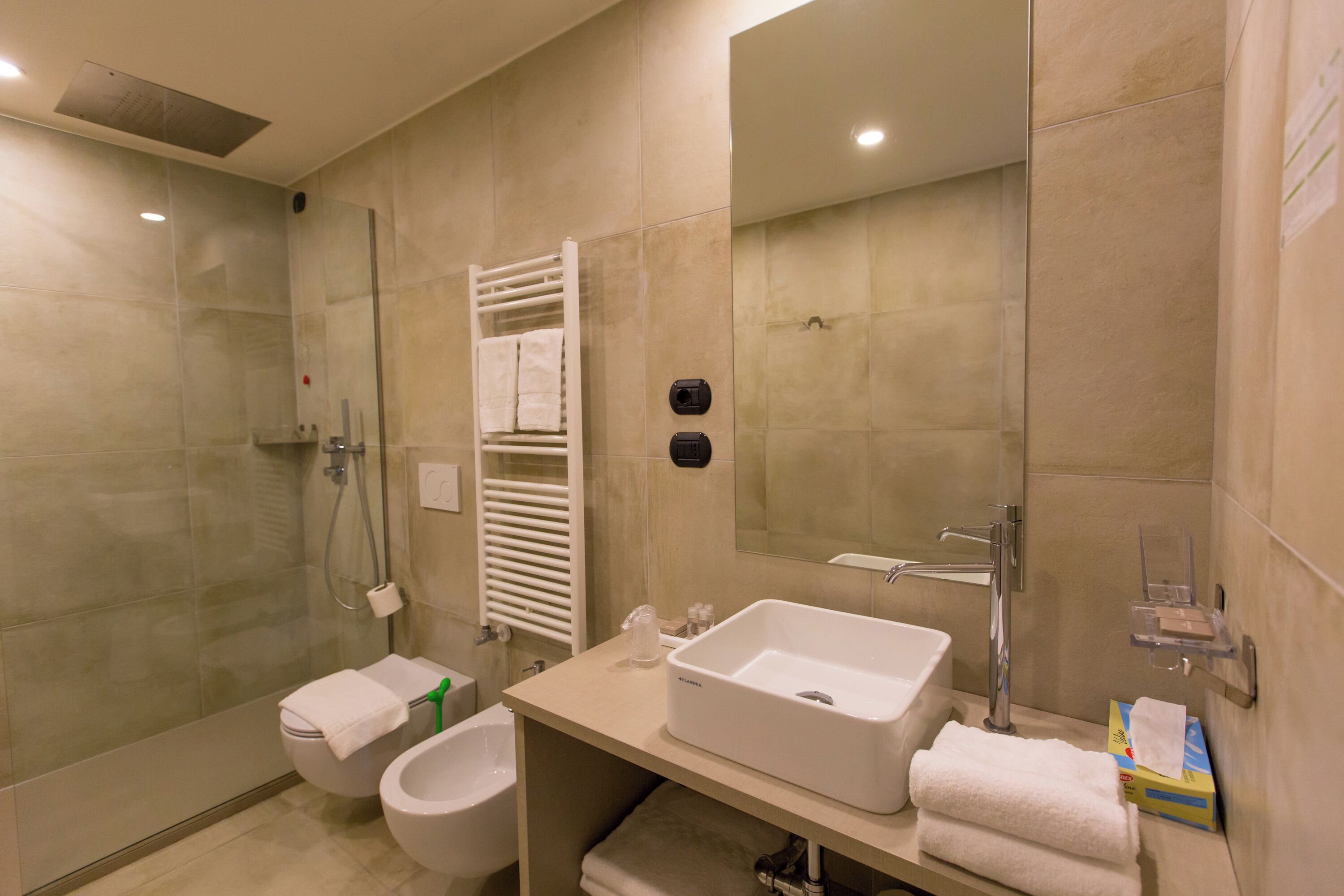 A modern bathroom with a glass-enclosed shower, a white sink, and a toilet.