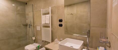 A modern bathroom with a glass-enclosed shower, a white sink, and a toilet.
