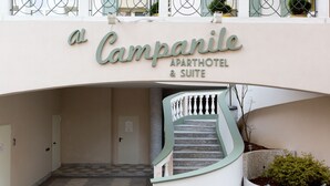 Entrada de um edifício com uma placa que diz 'Campanile Apartment & Suite'.
