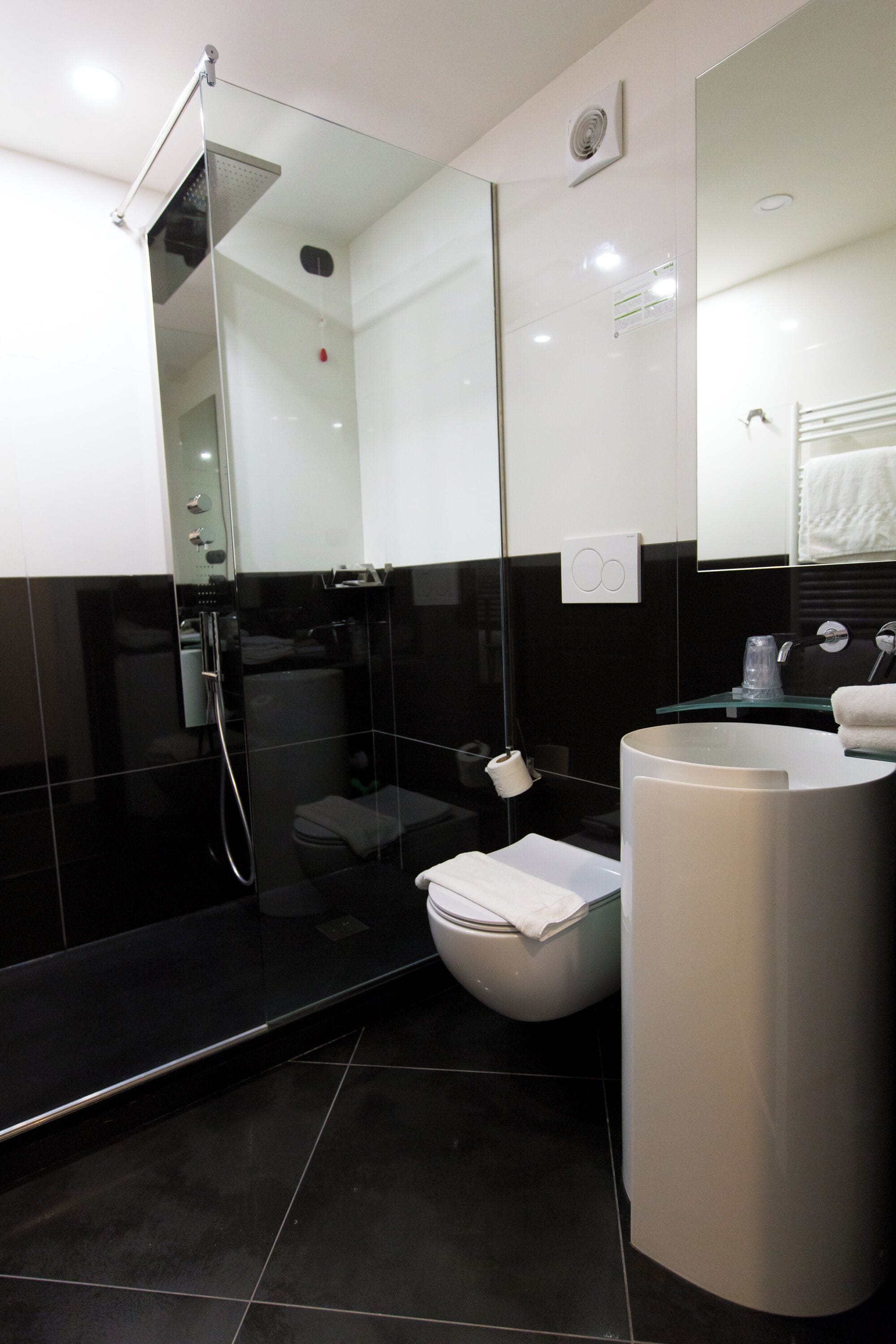 A modern bathroom with a glass-enclosed shower, a white toilet, and a large sink.