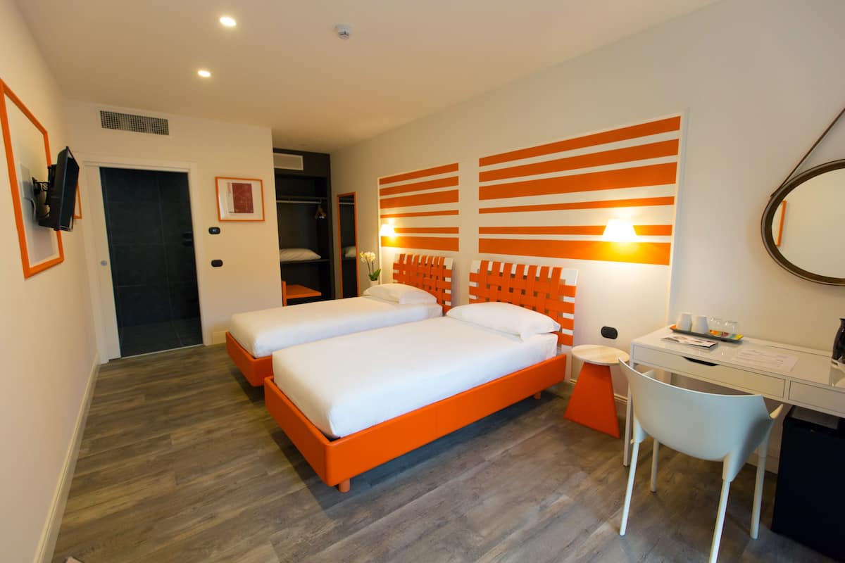 Ein Hotelzimmer mit einem Doppelbett, einem Schreibtisch mit Stuhl und einem Spiegel an der Wand.