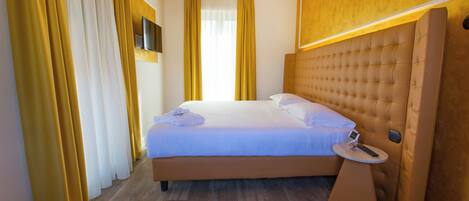 Ein modernes Hotelzimmer mit einem großen Bett, einem Nachttisch und einem an der Wand befestigten Fernseher.