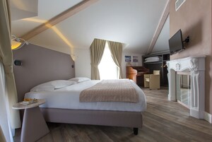 Un dormitorio con una cama, mesita de noche y televisor montado en la pared.