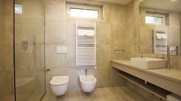A modern bathroom with a glass-enclosed shower, a toilet, a bidet, and a large mirror.