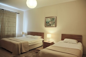 A hotel room with two beds, a nightstand with a lamp, a painting on the wall, and a window with curtains. - Airport Residence Kurtkoy (Istanbul)