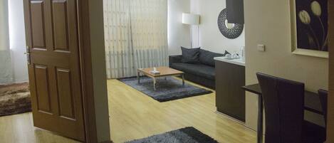 Una sala de estar con puerta de madera, un sofá, una mesa de centro, una lámpara y un sillón.