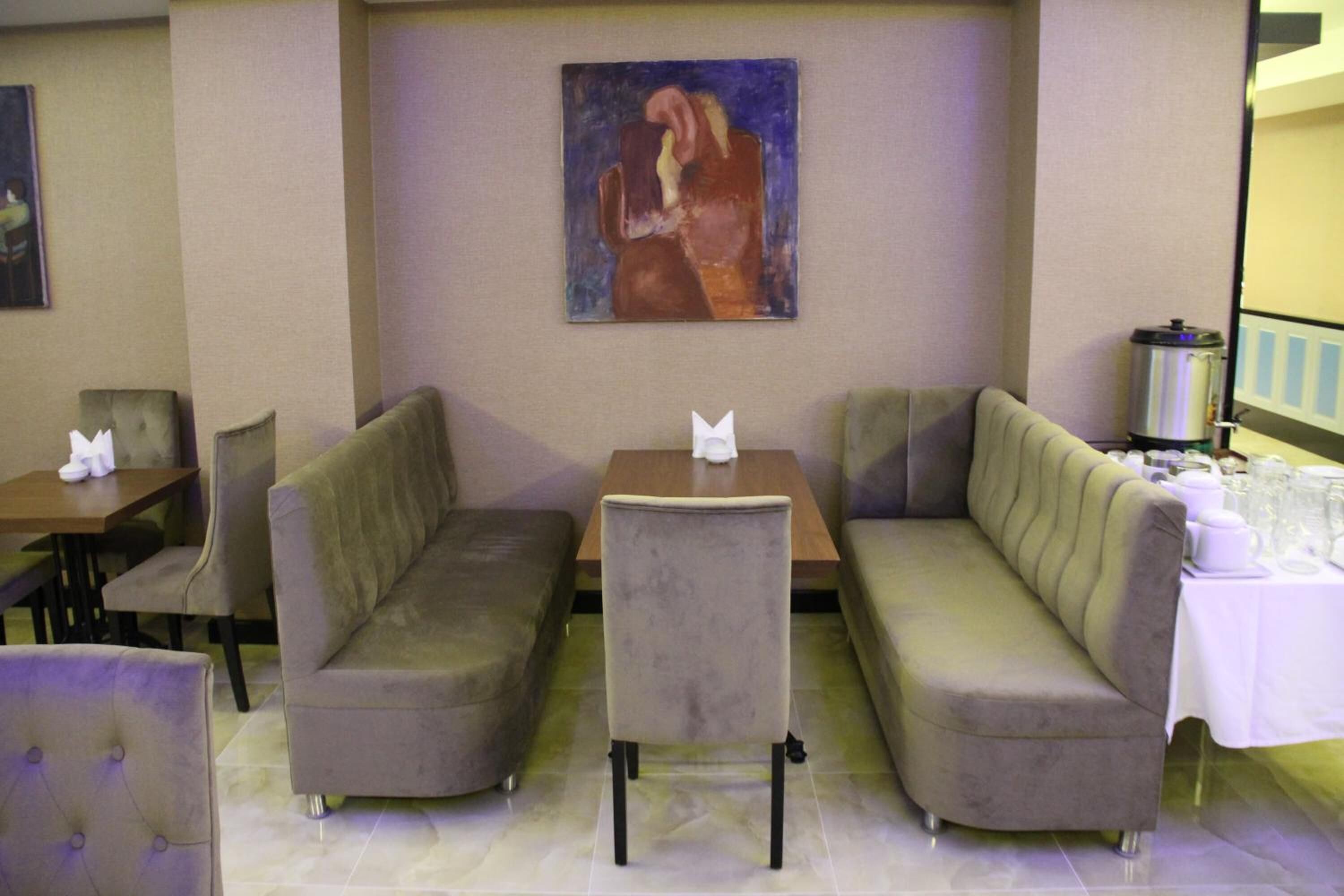 A seating area with two sofas and a table, a painting on the wall, and a coffee machine.