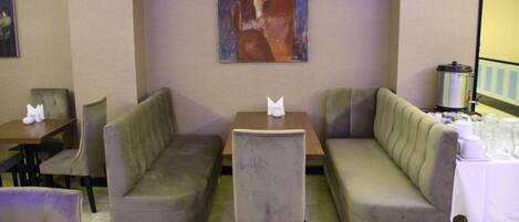 A seating area with two sofas and a table, a painting on the wall, and a coffee machine.