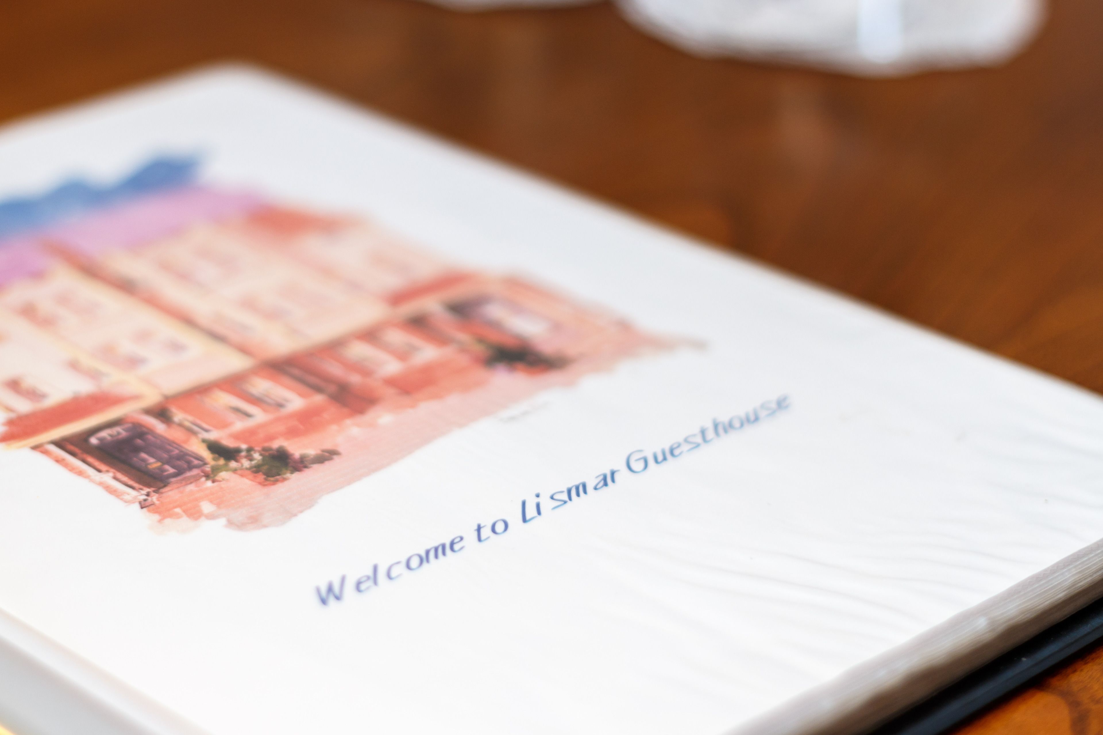 Eine Broschüre mit Illustration eines Gebäudes und dem Text 'Welcome to Li Smar Guesthouse'.