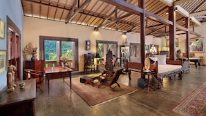 A spacious room with a large bed, wooden furniture, and a view of lush greenery outside. - Villa Patria (Sukasada)