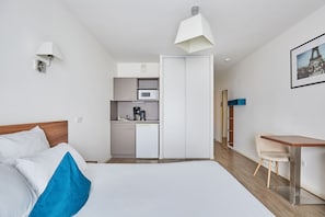 A hotel room with a bed, a desk, a kitchenette, and a wardrobe. - Appart'hôtel Odalys City Campus - Paris Rueil Malmaison (Rueil-Malmaison)