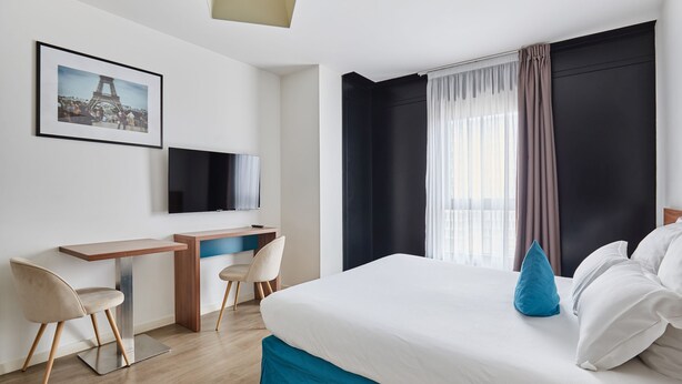 A modern hotel room with a large bed, a desk with a chair, a television, and a picture of the Eiffel Tower on the wall. - Appart'hôtel Odalys City Campus - Paris Rueil Malmaison (Rueil-Malmaison)