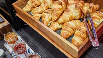 Uma bandeja de madeira com croissants e dois potes de geleia.
