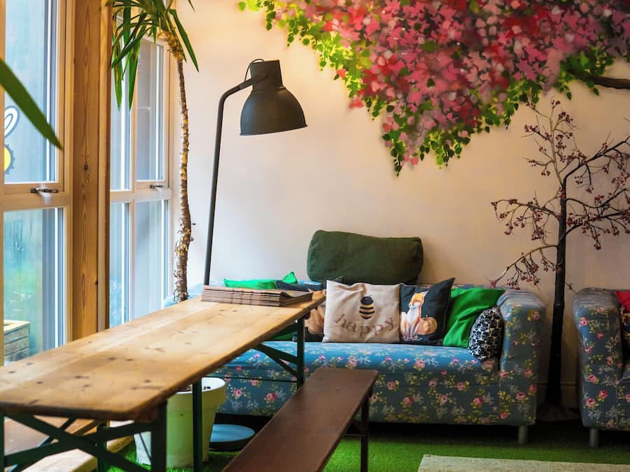 A cozy room with a wooden table, bench, sofa, and a decorative wall with a floral pattern.