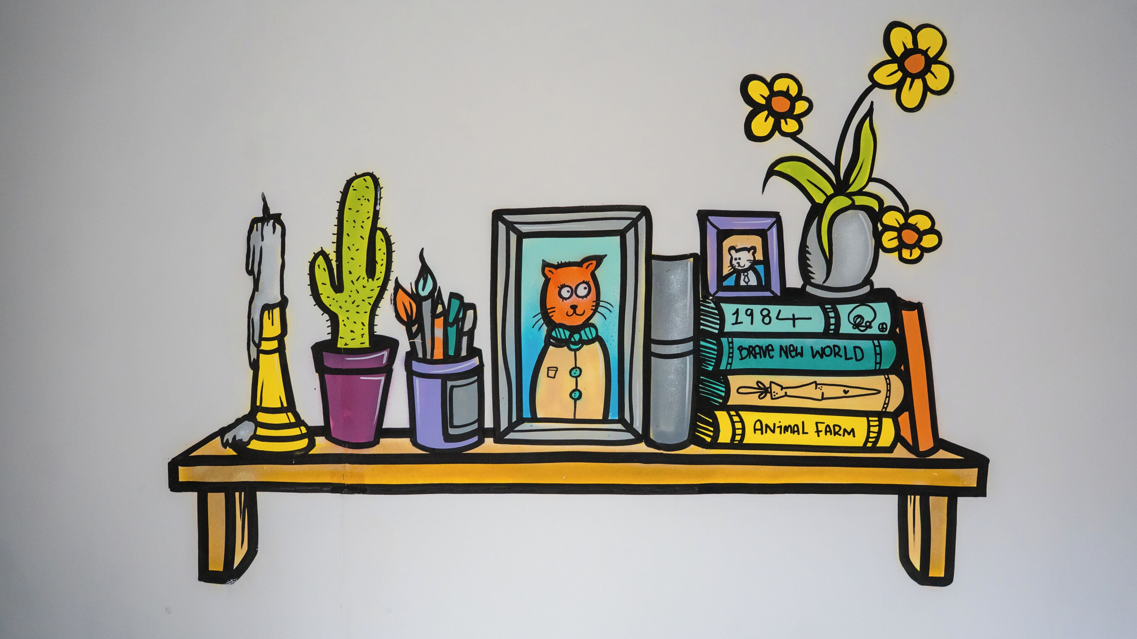A shelf with a cactus, a framed picture of an orange cat, a vase with flowers, and books titled '1984' and 'Animal Farm'.