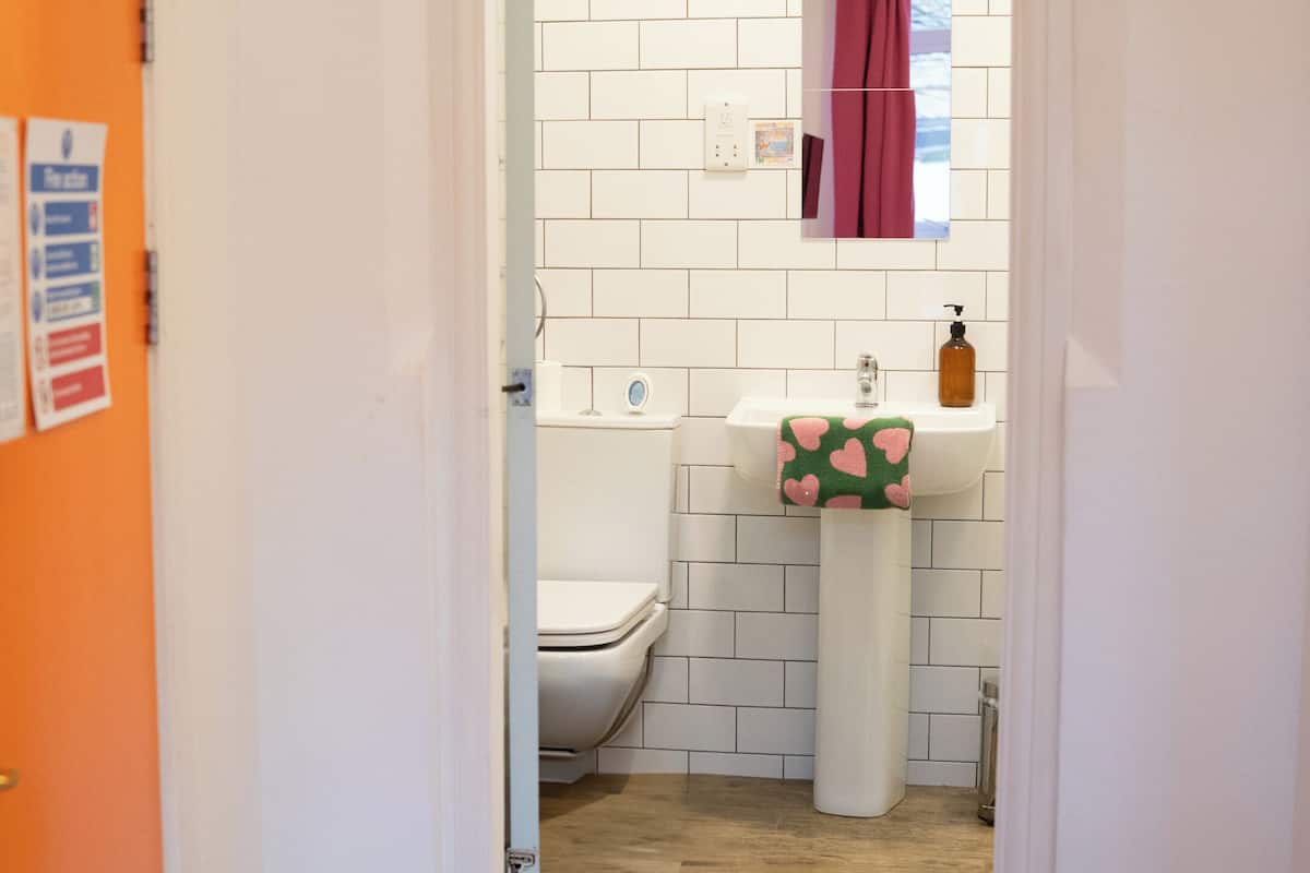 A hallway leading to a bathroom with a toilet, sink, and a towel rack.