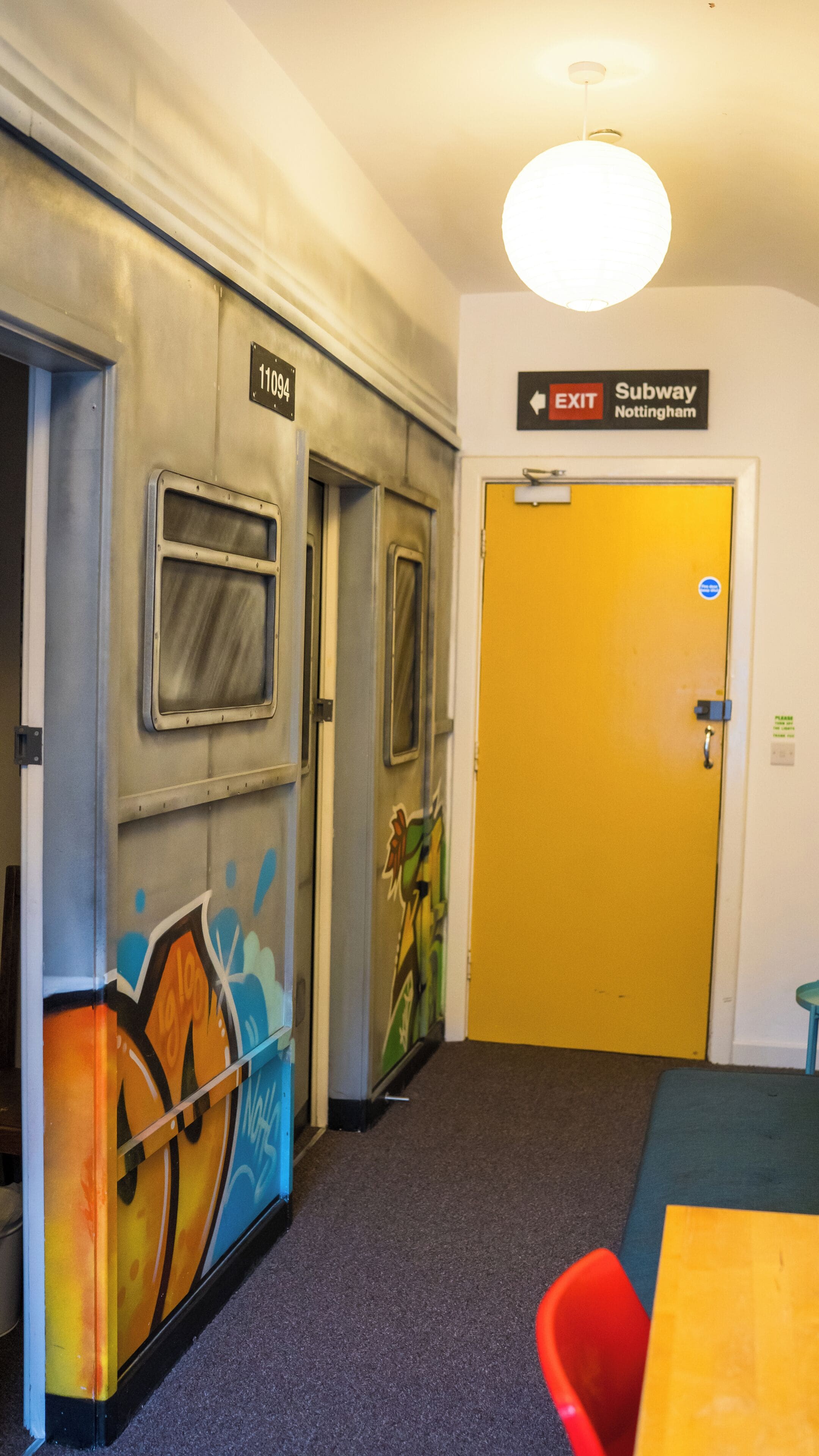 Un couloir avec un panneau indiquant la sortie, un panneau indiquant la sortie du métro, et une porte recouverte de graffitis.