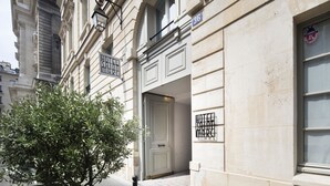 A building facade with a classical architectural style, featuring a large arched window, a door with a metal gate, and a small tree in front. - Hotel Saint-Marc (Paris)