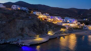 Un pueblo costero con edificios blancos, una carretera pavimentada y barcos en el agua.
