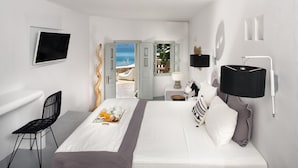 Habitación de hotel moderna con cama, televisor, escritorio y vista a la playa.