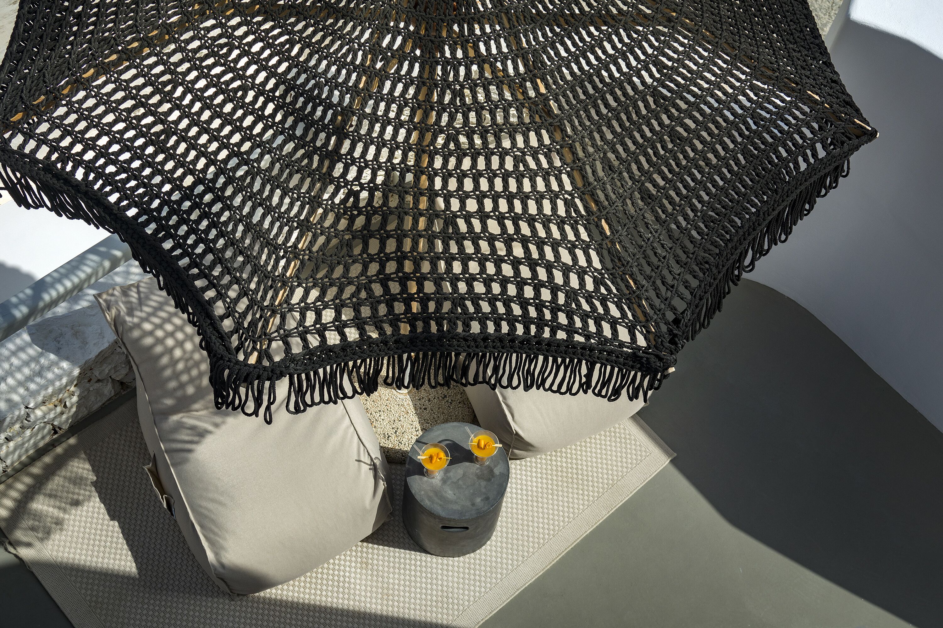 Un espace extérieur aménagé avec des meubles en osier, des coussins et une petite table décorée de bougies.