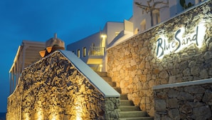 A stone wall with the name "BlueSand" illuminated, a staircase, and a building with balconies.