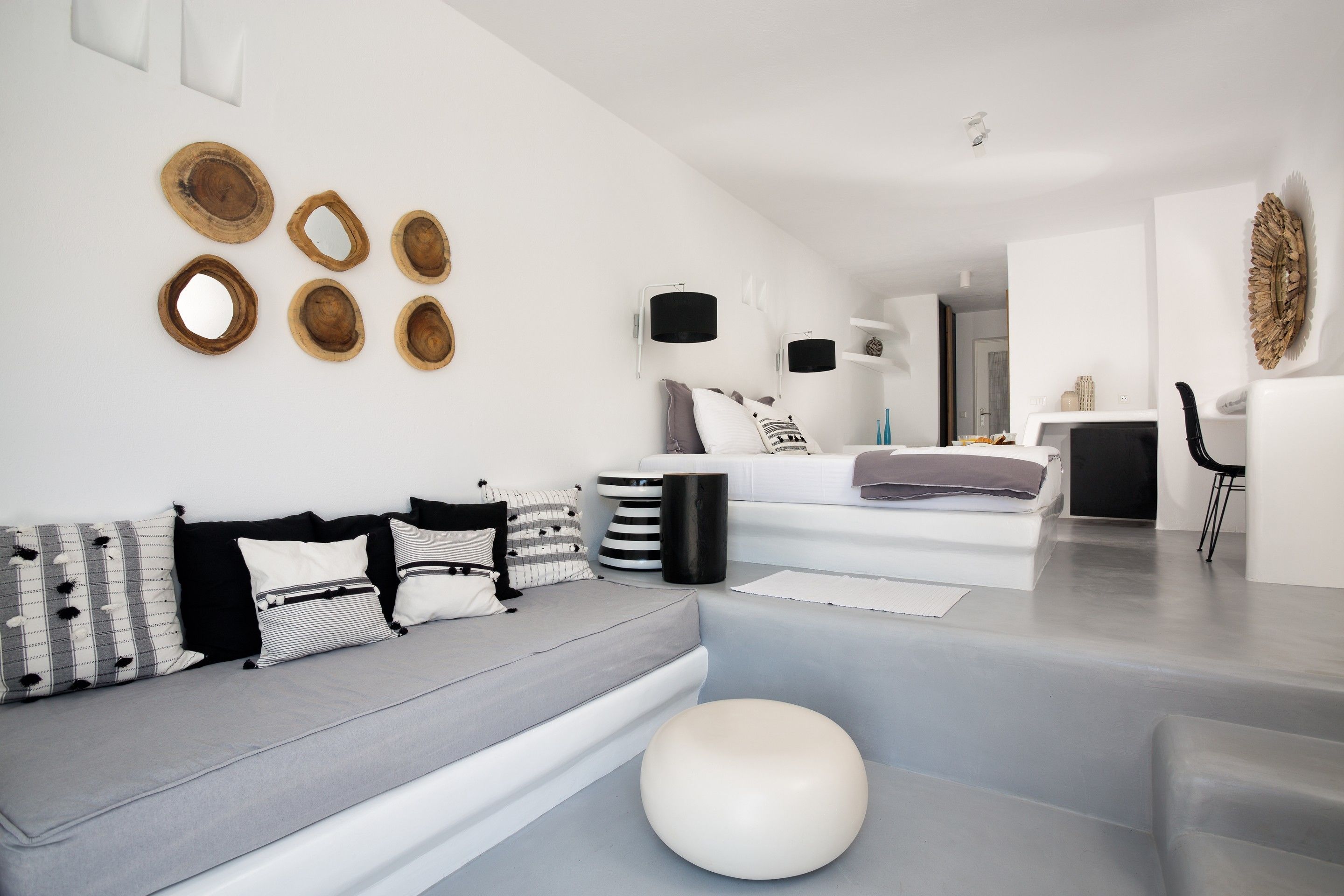 A modern living room with a grey sofa, white cushions, and a round white ottoman.