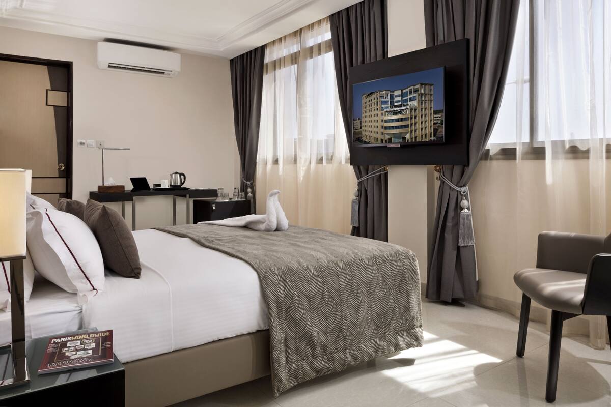 Une chambre d’hôtel équipée d’un lit, d’un bureau, d’une chaise, d’une télévision et d’une fenêtre avec des rideaux.